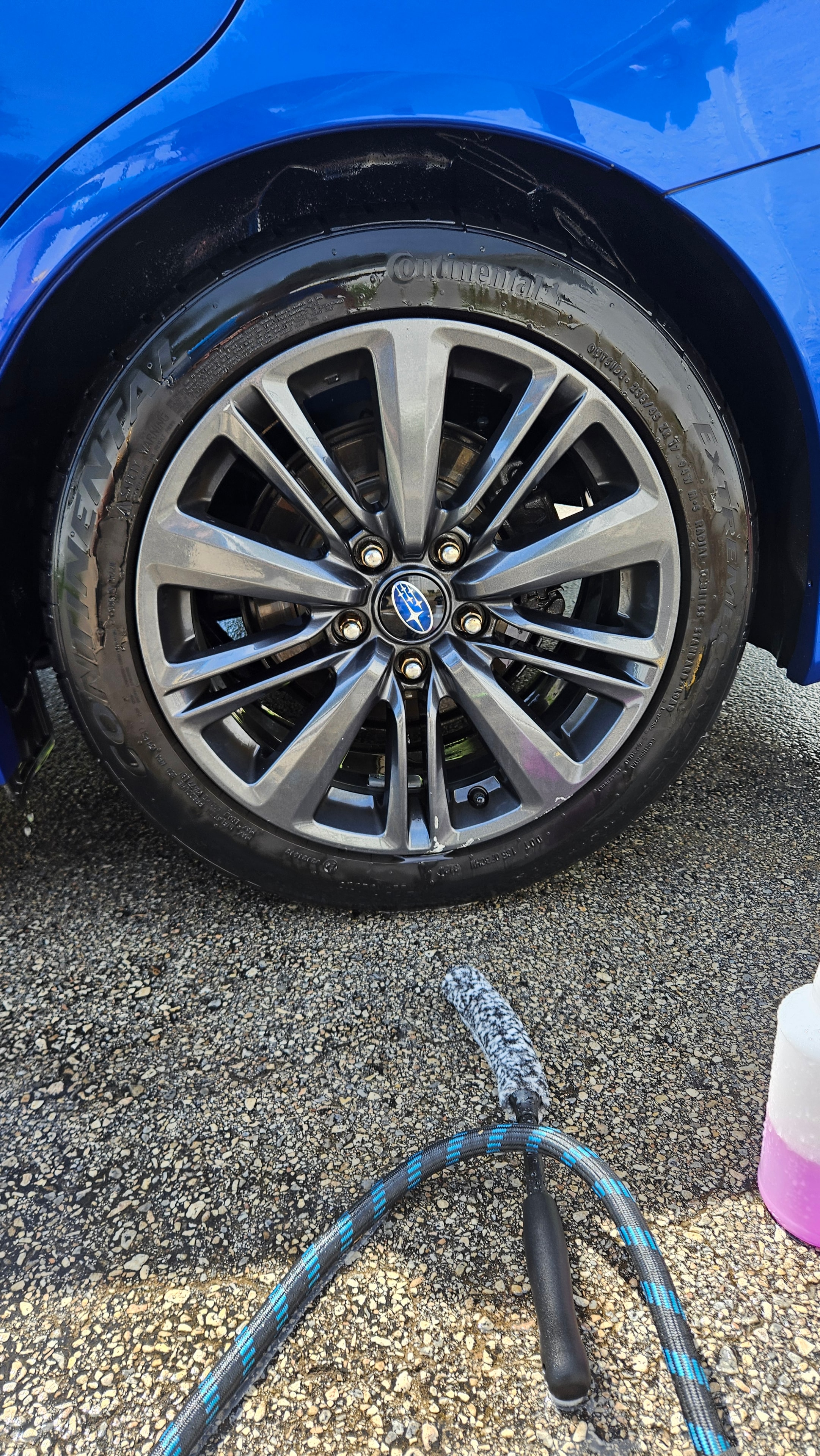 Blue Subaru wheel and tire during a professional wash